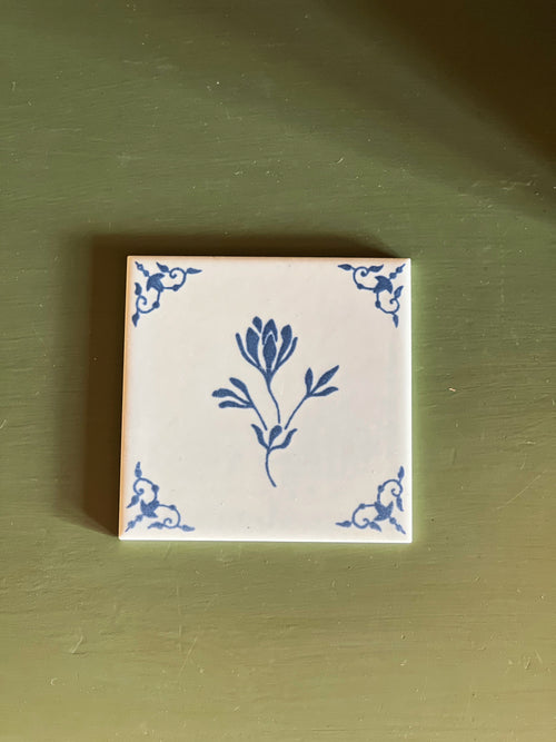 Decorative tile with blue floral design on a green background