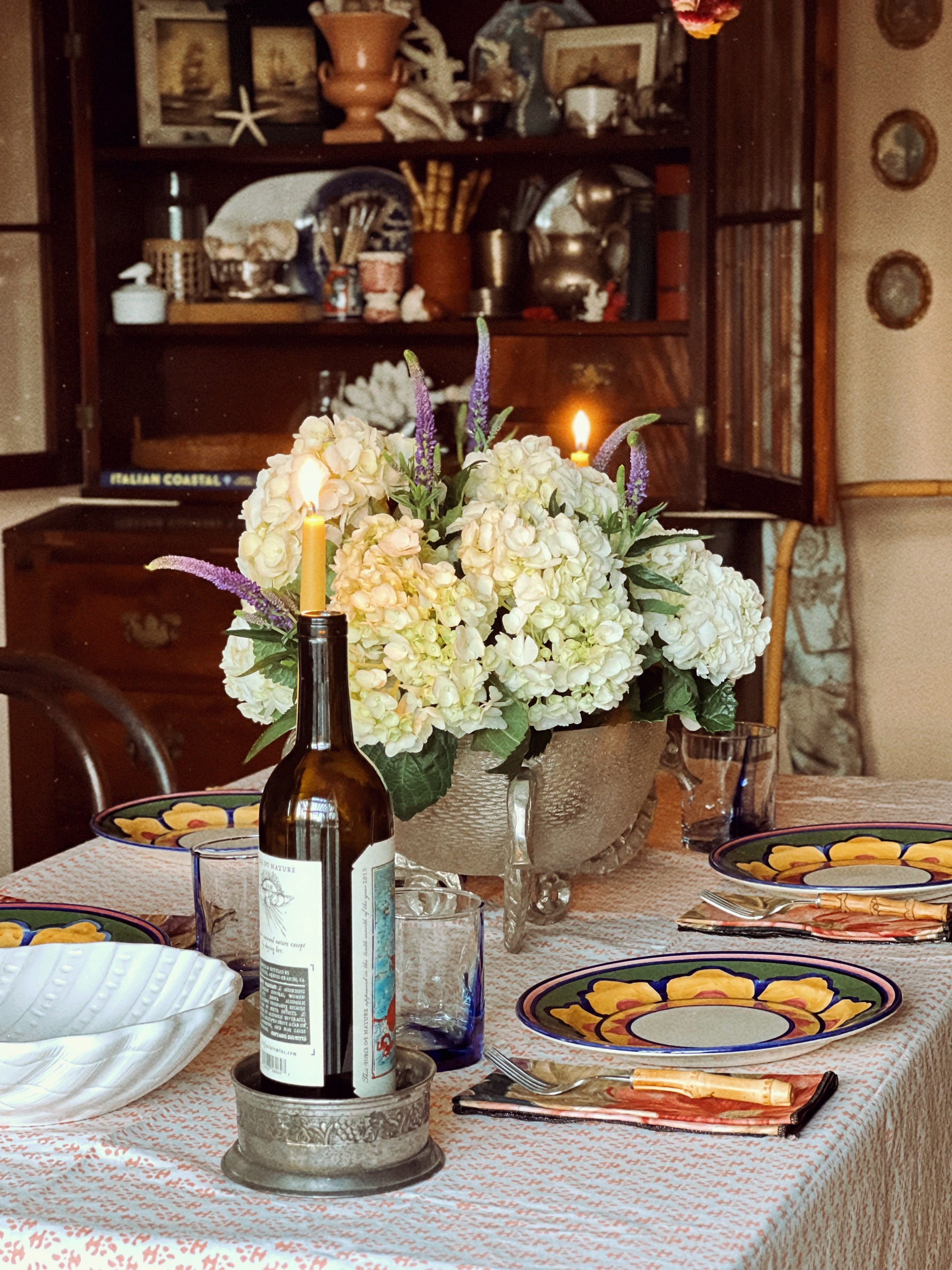 Vintage wine coaster styled on a dining table with candle holders and floral arrangement