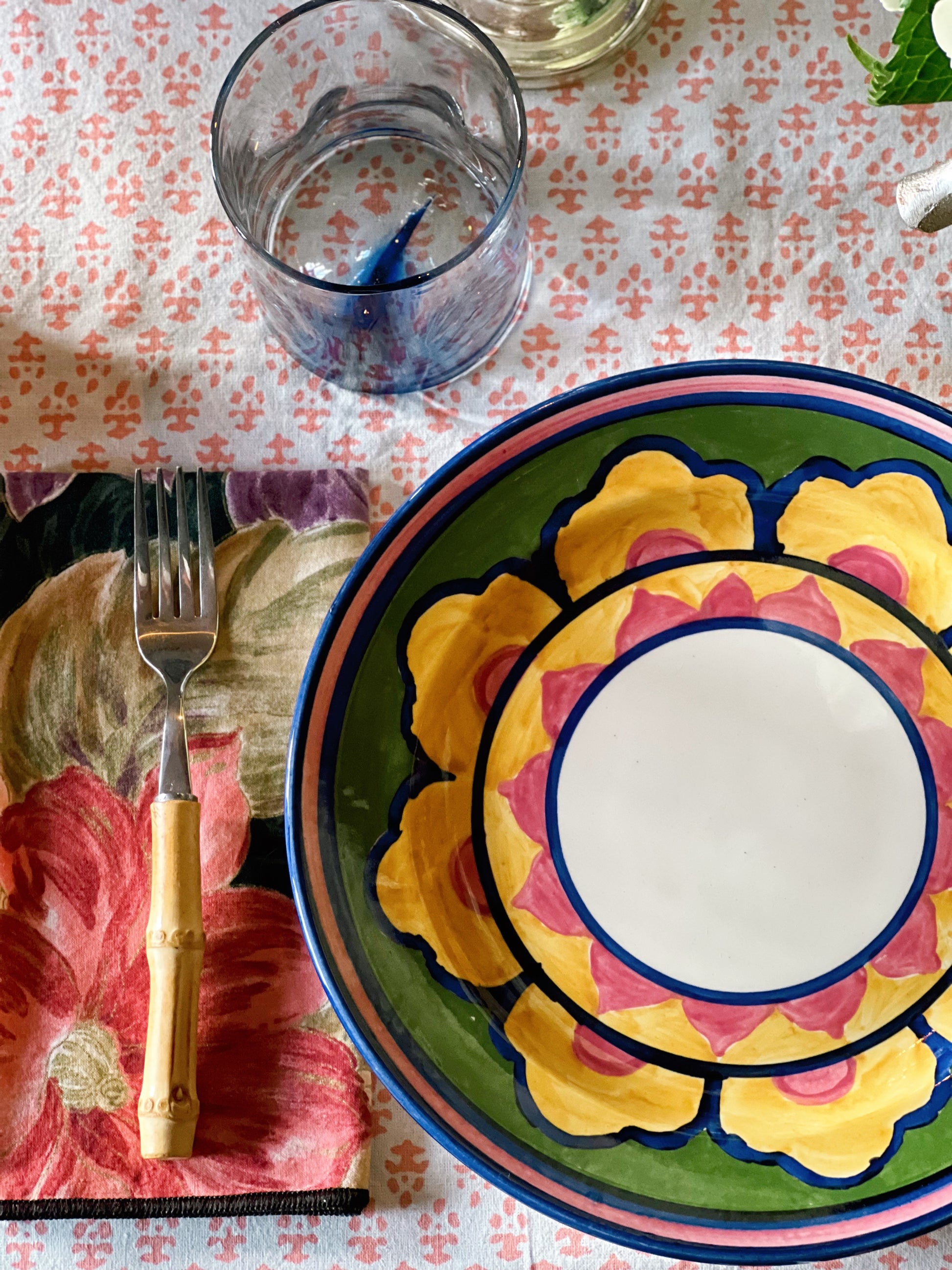 Colorful vintage floral dinner plates layered in a styled table setting with glassware and linens