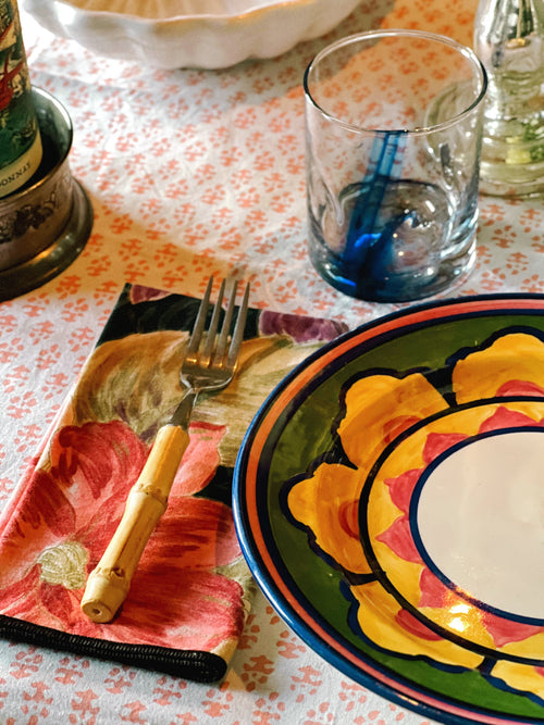 Vintage floral cloth napkins layered in a colorful table setting with patterned dinnerware