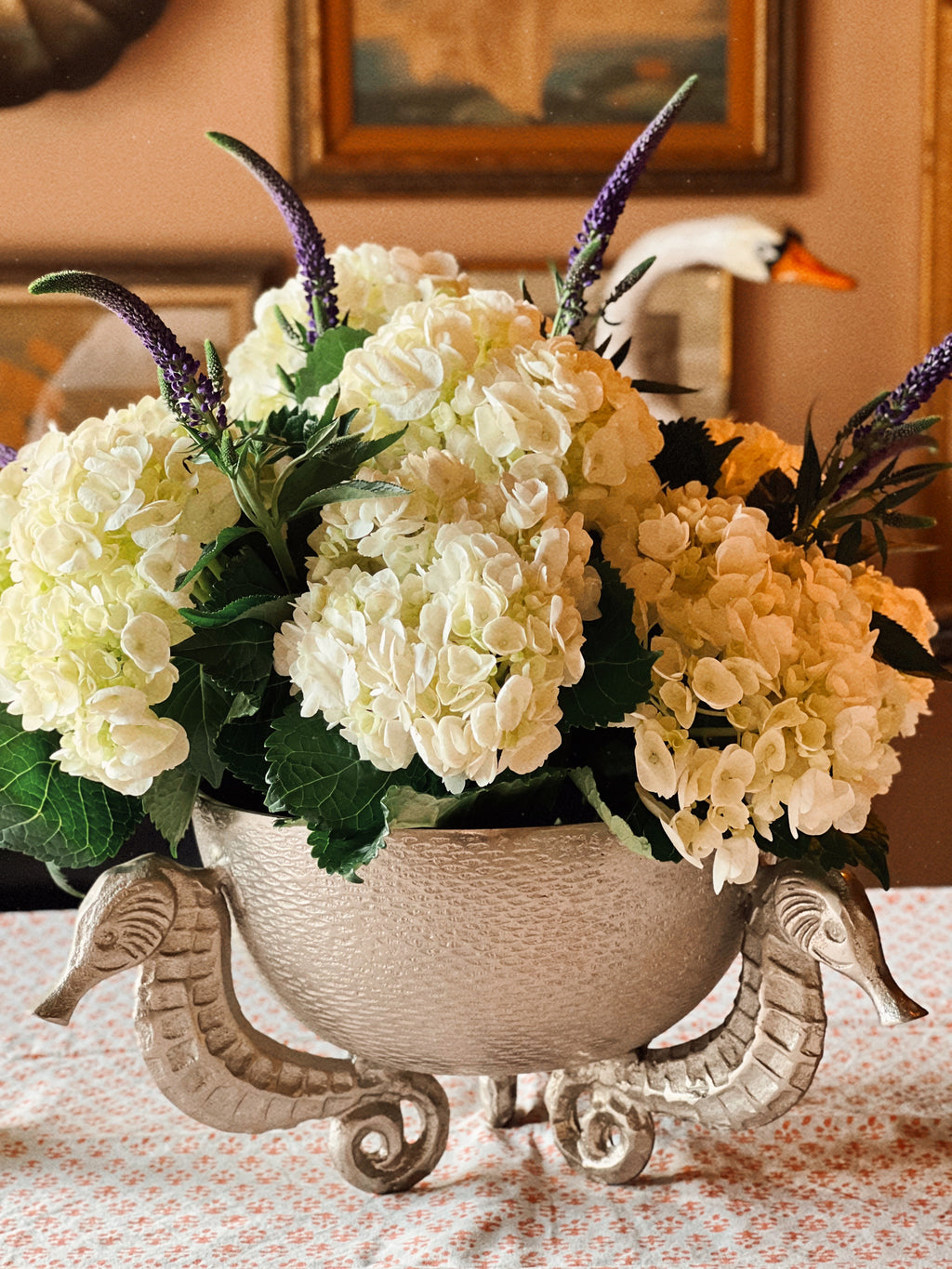 Coastal table setting with vintage silver seahorse bowl centerpiece and layered dinnerware
