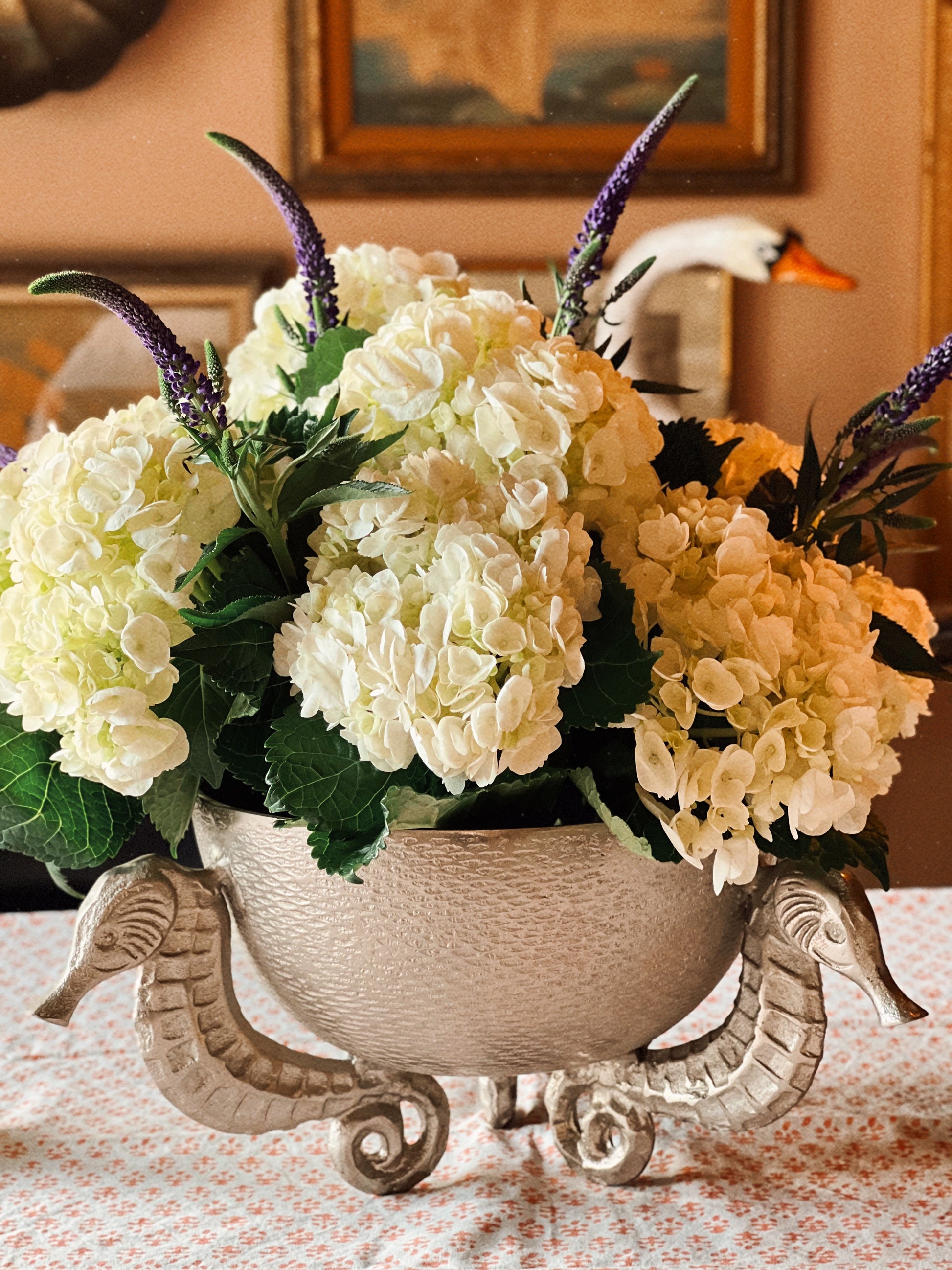 Coastal table setting with vintage silver seahorse bowl centerpiece and layered dinnerware