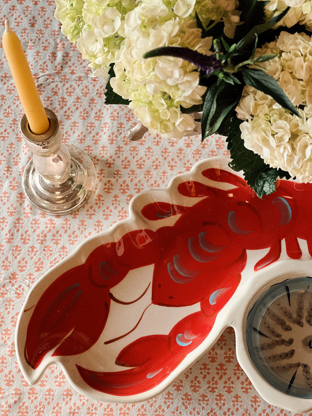 Red lobster chip and dip serving platter on a coastal table setting with hydrangeas