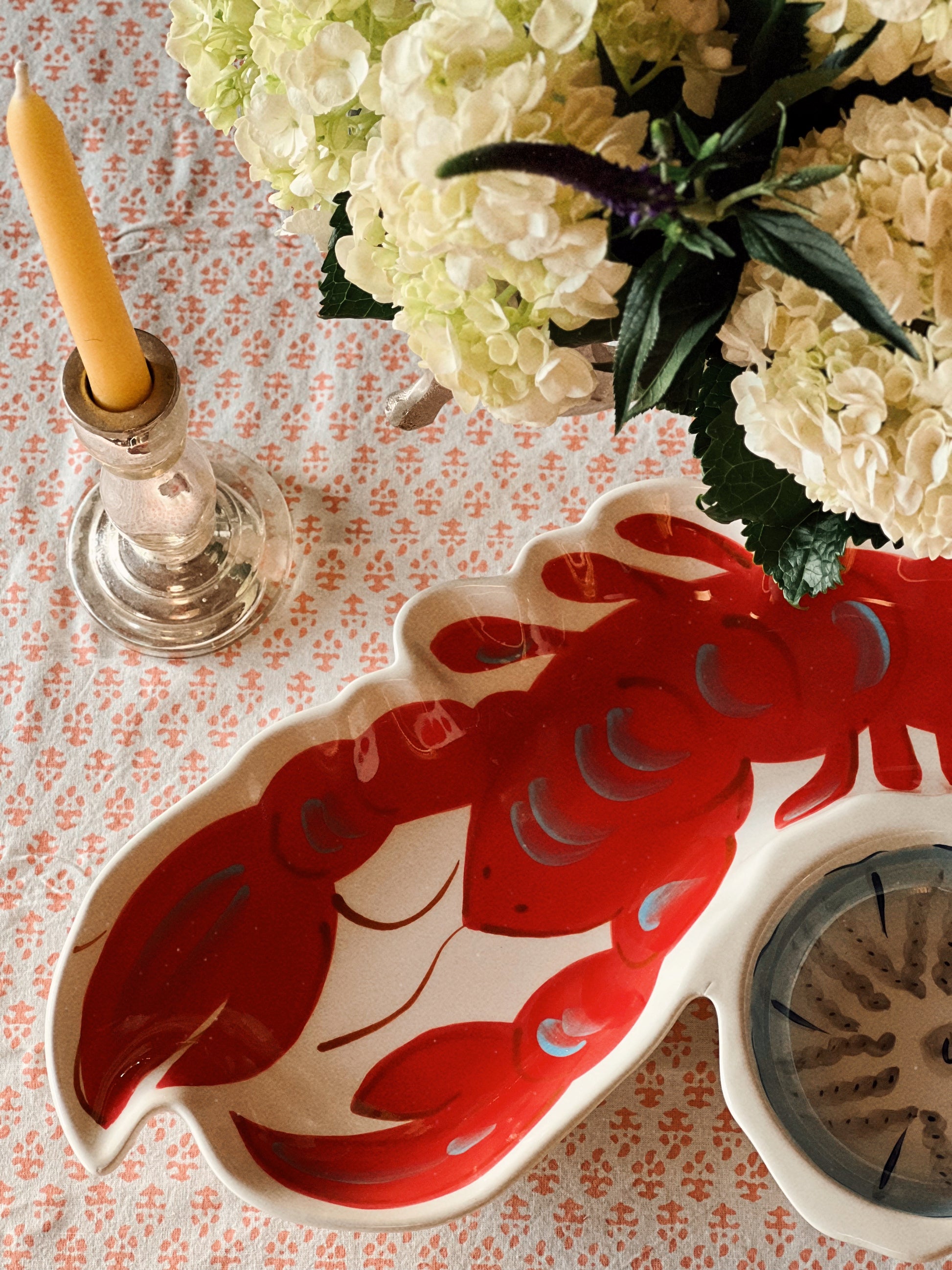 Red lobster chip and dip serving platter on a coastal table setting with hydrangeas