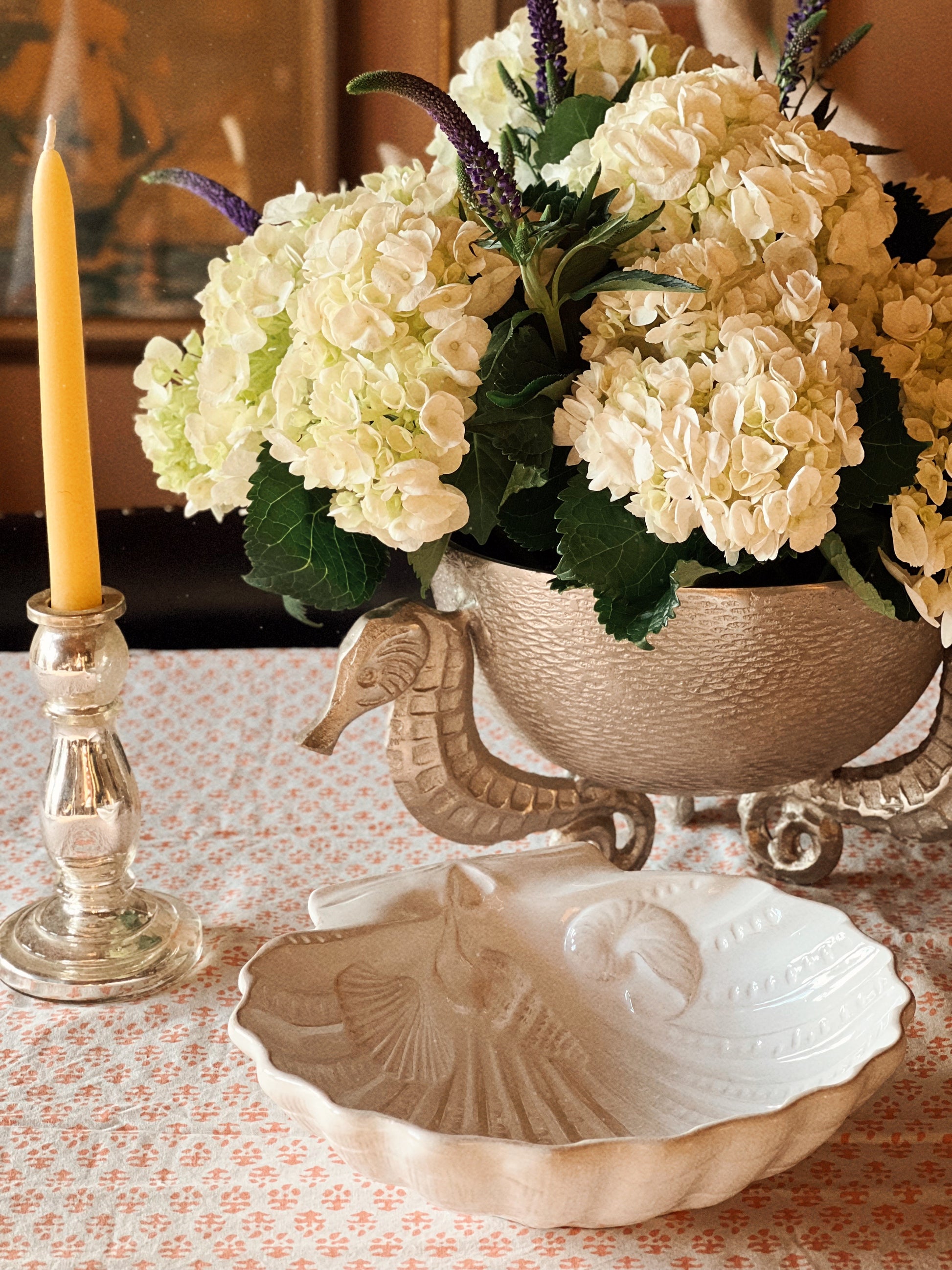 Coastal table setting with white scallop shell dish and layered serveware