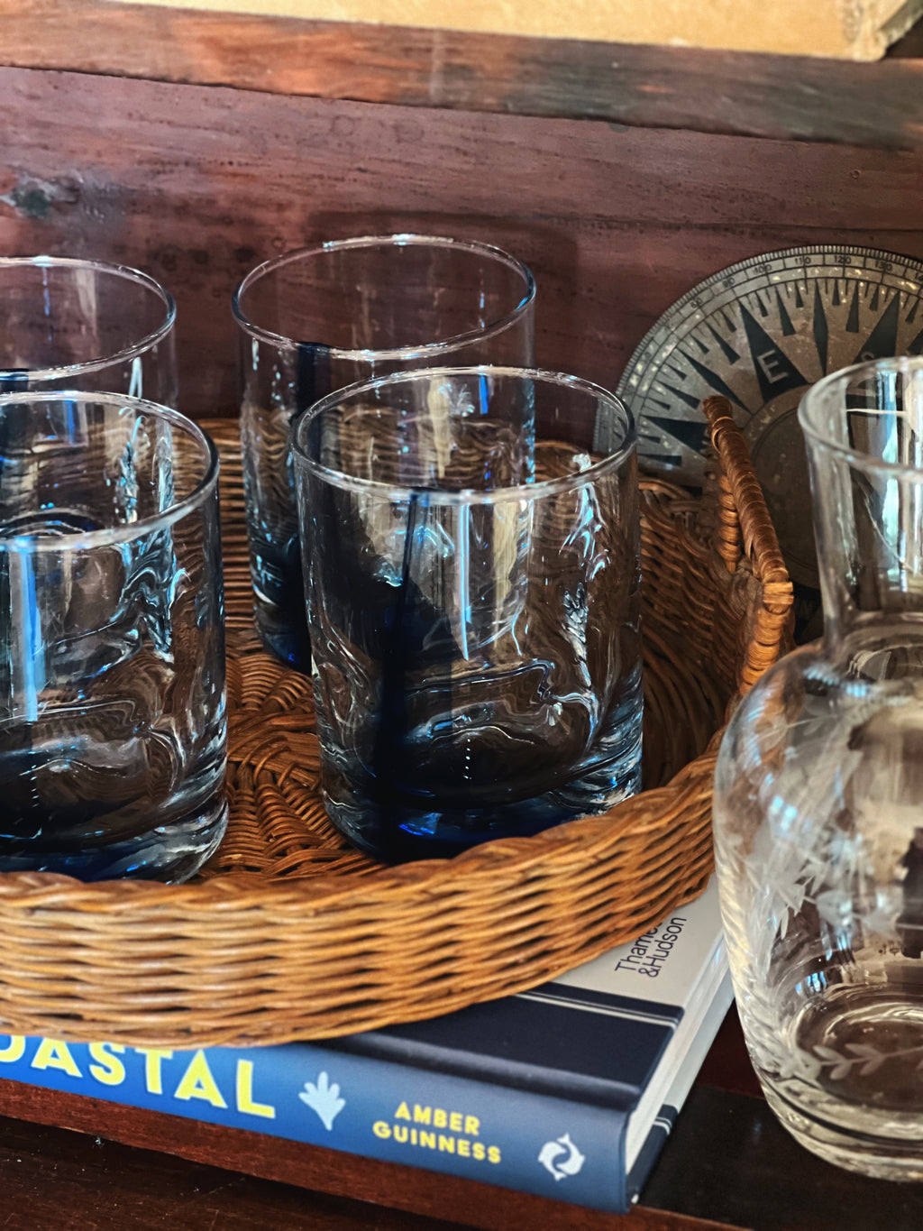 Woven serving tray with blue swirl glasses, vintage barware display