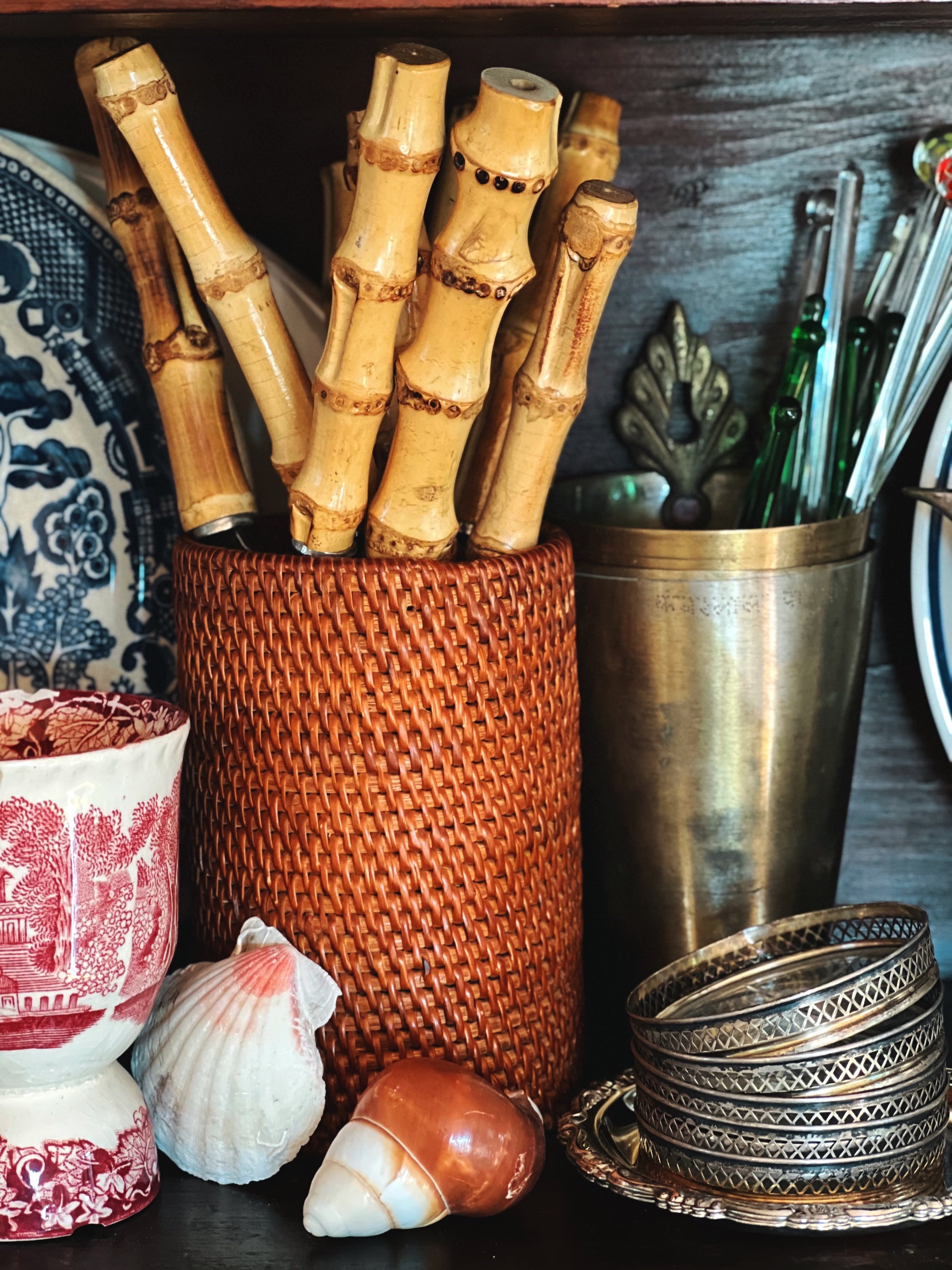 Woven rattan utensil holder filled with bamboo flatware styled with coastal decor