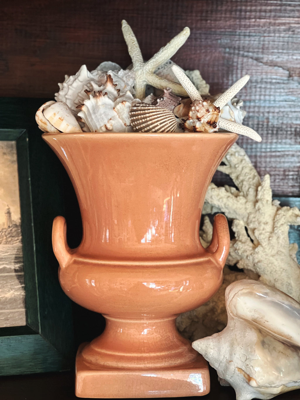 Vintage glazed pottery urn with handles in soft peach pink finish styled with neutral decor