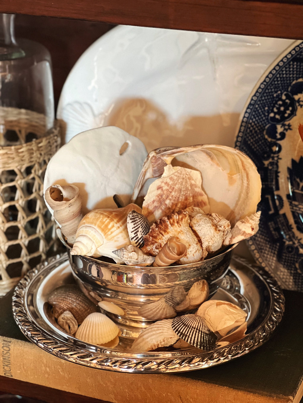 Silver serving bowl with attached underplate styled with natural elements on shelf