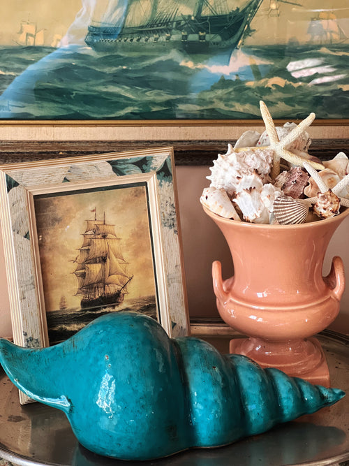 Large blue shell decorative object in layered coastal vignette