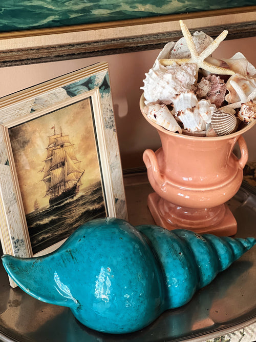 Vintage blue ceramic shell sculpture styled on shelf with coastal decor