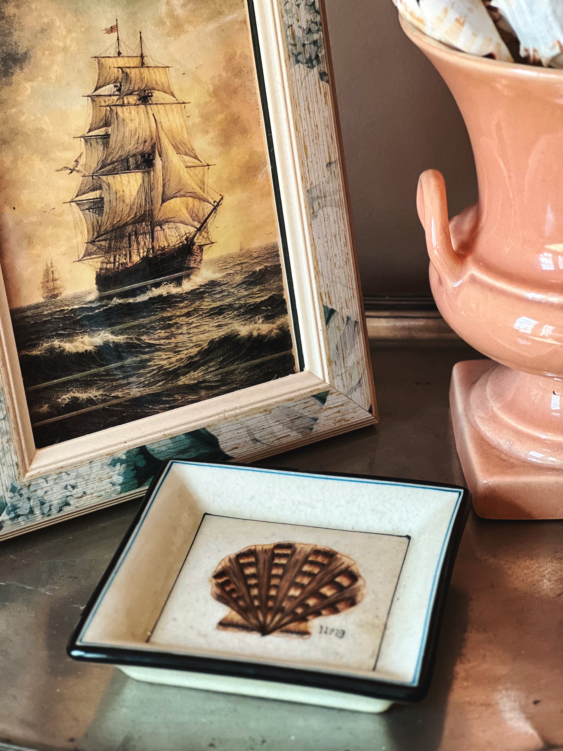 Vintage porcelain shell trinket dish styled with coastal decor and framed art