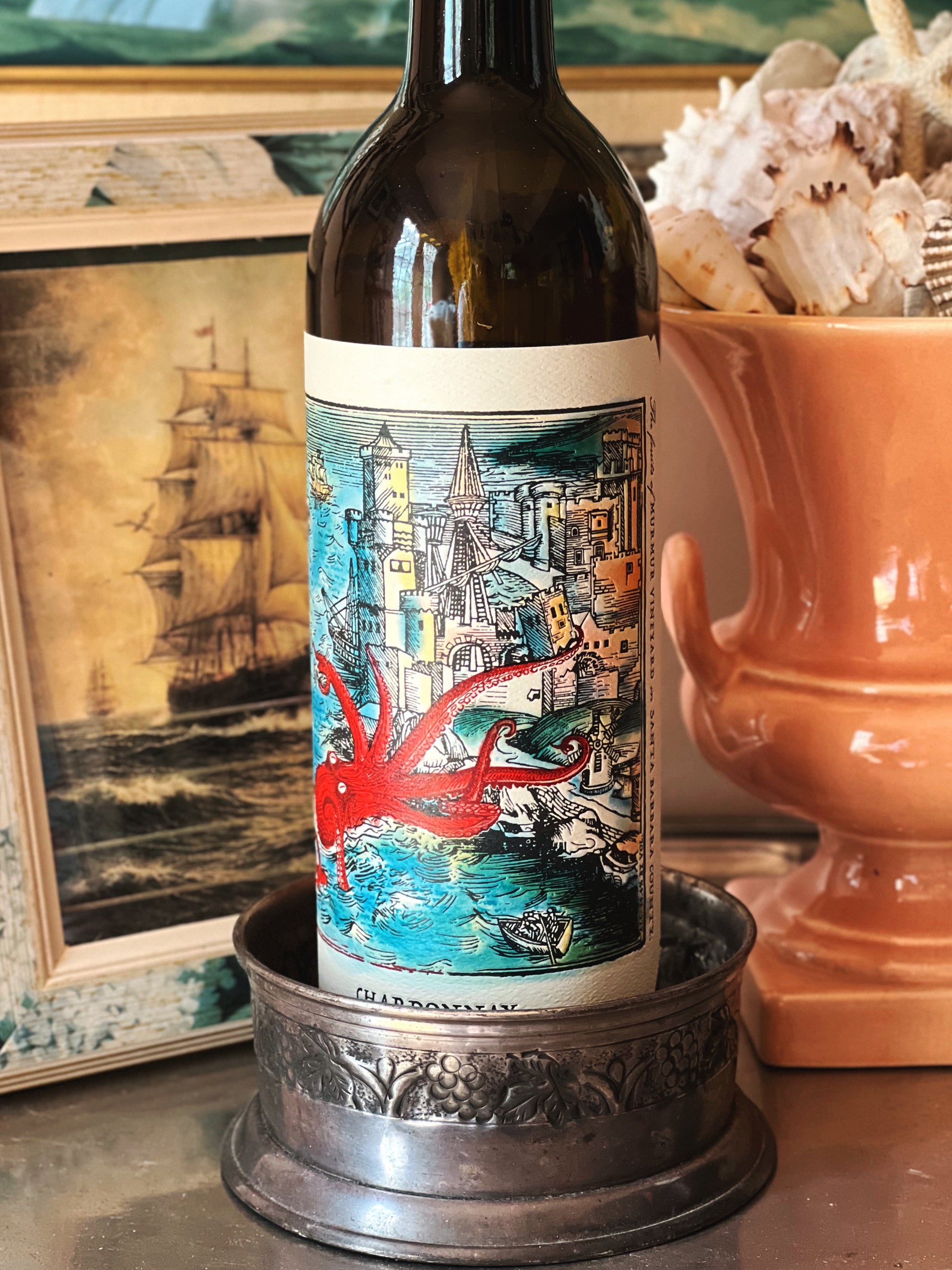 Silver wine bottle coaster with embossed grapevine design used as a base for a wine bottle