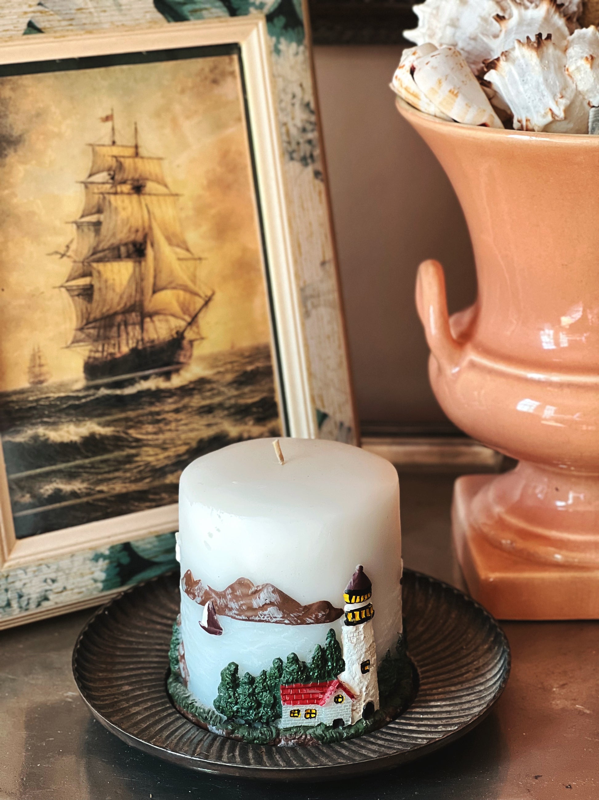 vintage lighthouse pillar candle coastal decor styled with nautical artwork and ceramics