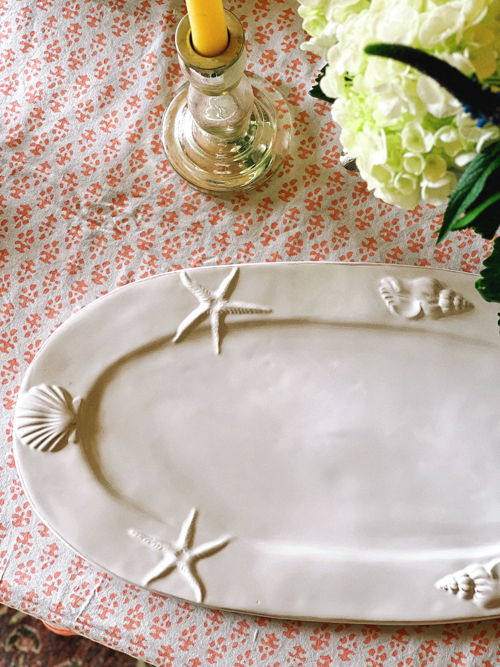 Coastal ceramic serving platter with shell and starfish detail styled on table