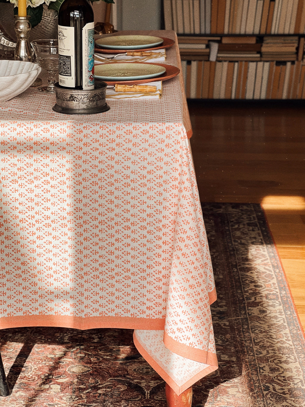 Apricot and white batik print tablecloth styled on a dining table with layered place settings