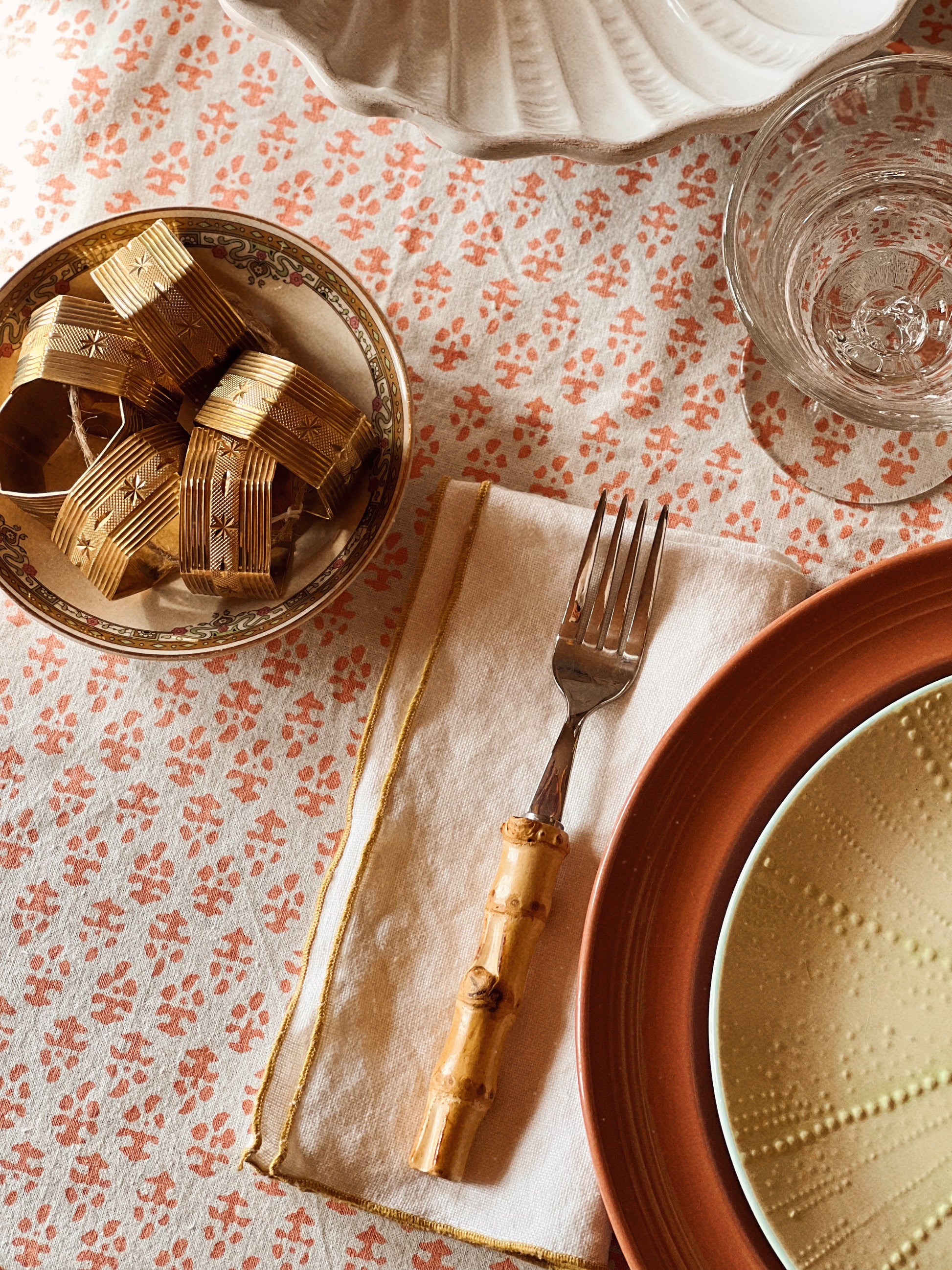 Brass starburst napkin ring styled at a place setting with layered plates and linens