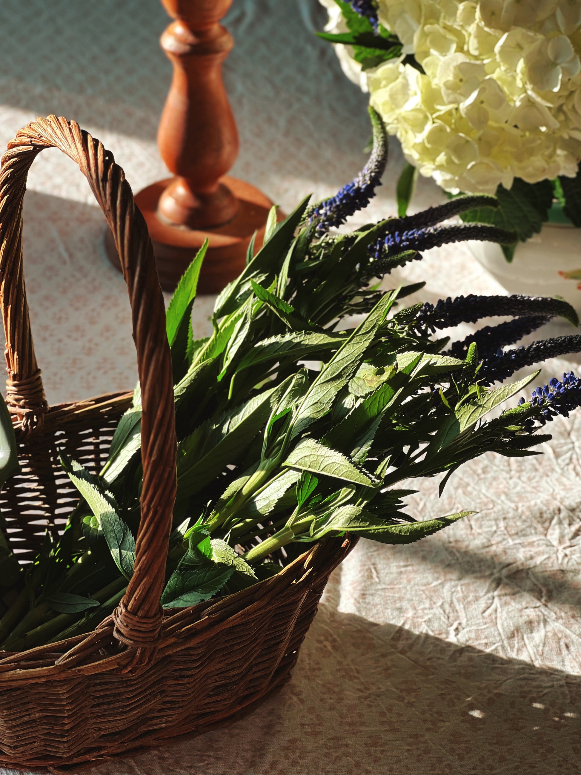 small willow basket filled with fresh greenery styled in natural light