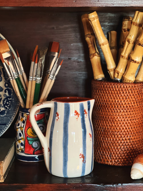 Striped creamer on a shelf styled with utensil holders