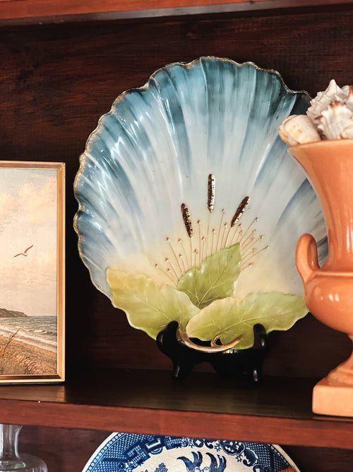 vintage scallop shell porcelain wall plate with blue and green detail styled on shelf with coastal decor