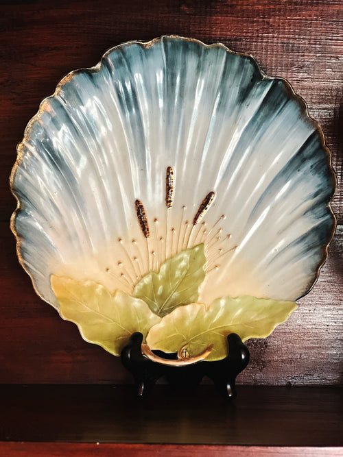 hand painted shell shaped wall plate in soft blue and green tones displayed as decorative accent