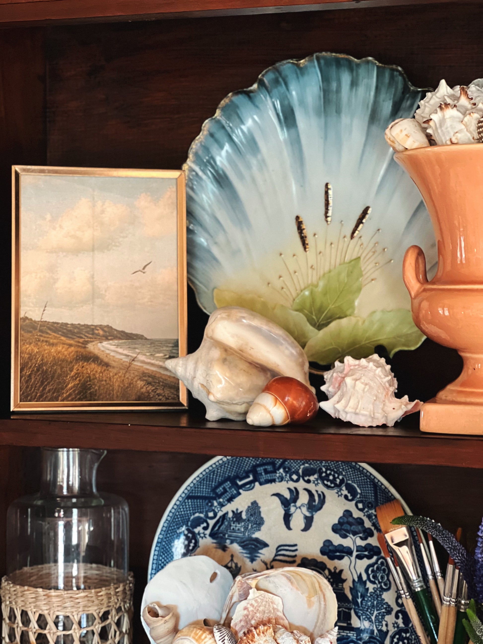 coastal porcelain wall plate with scalloped form styled with ceramic vessel and layered shelf decor