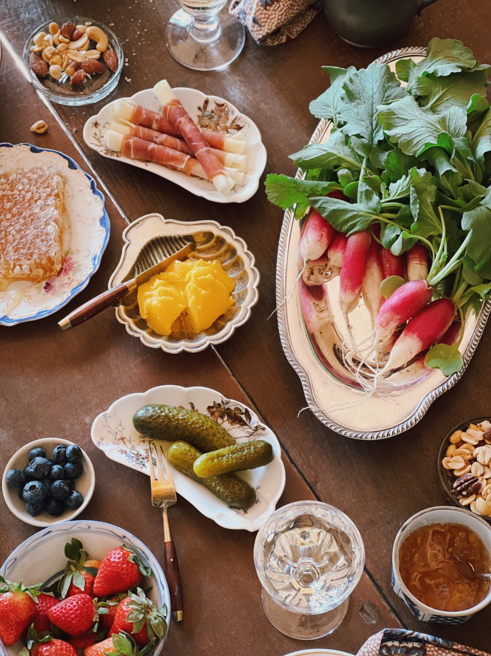 oval vintage silver tray full of radishes on a table with charcuterie and small bites
