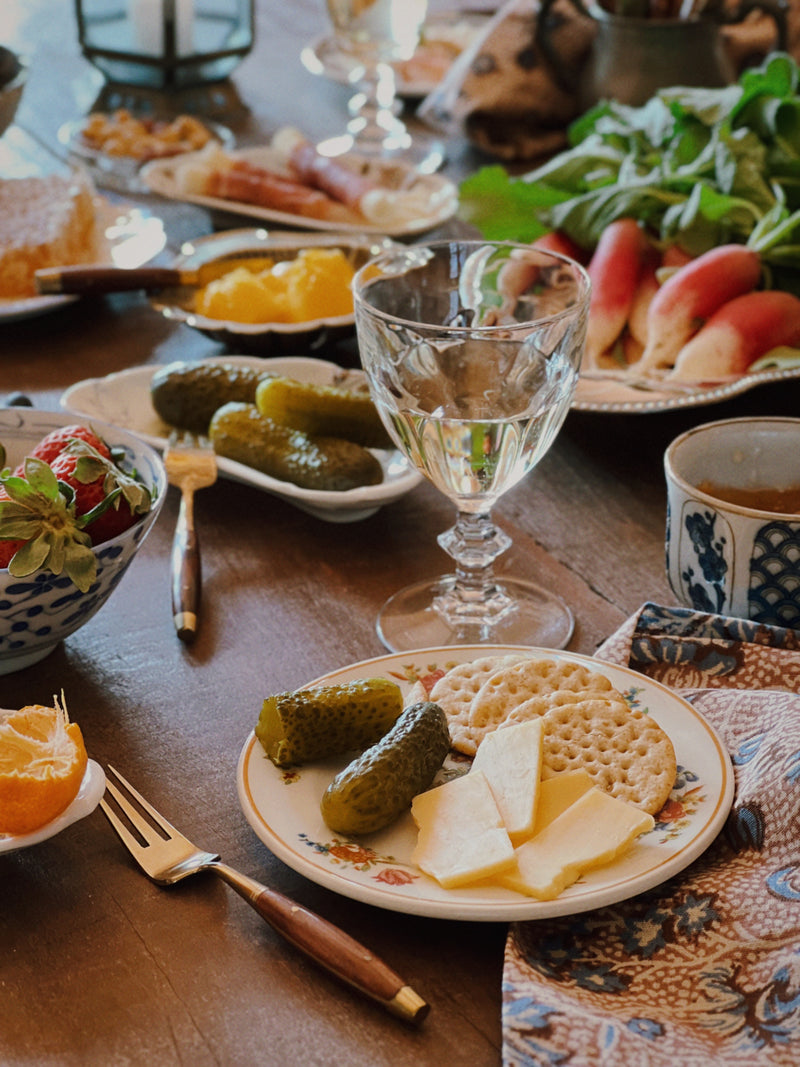 Set of four vintage petite wine glasses styled on a table with fruit, cheese, and layered vintage tableware
