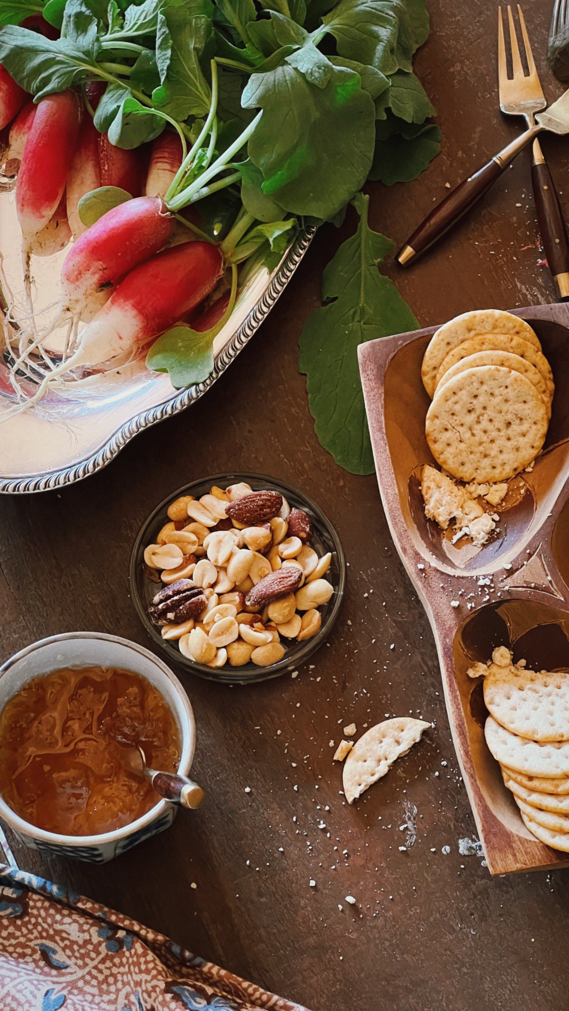 small glass dish with nuts on a table with charcuterie