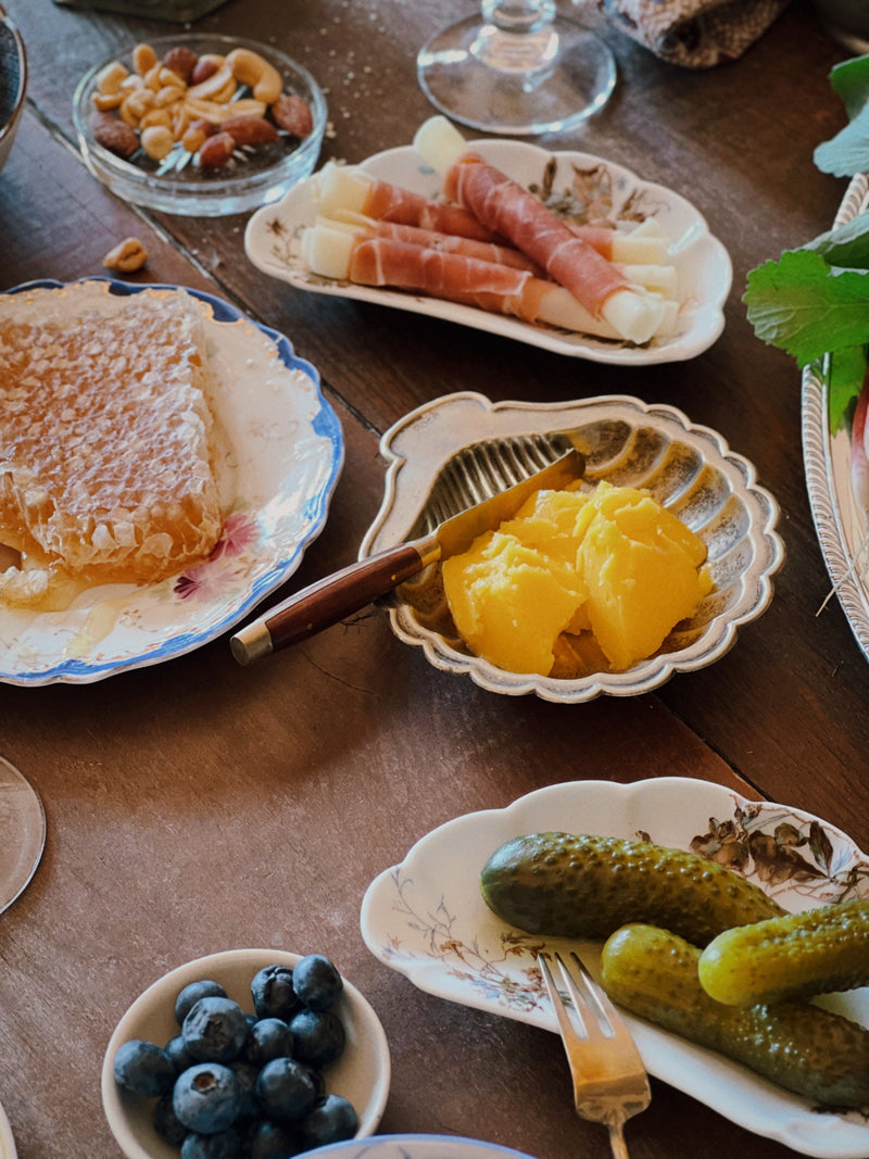 antique limoges bone dish used for pickles on a vintage table with glassware and shared plates