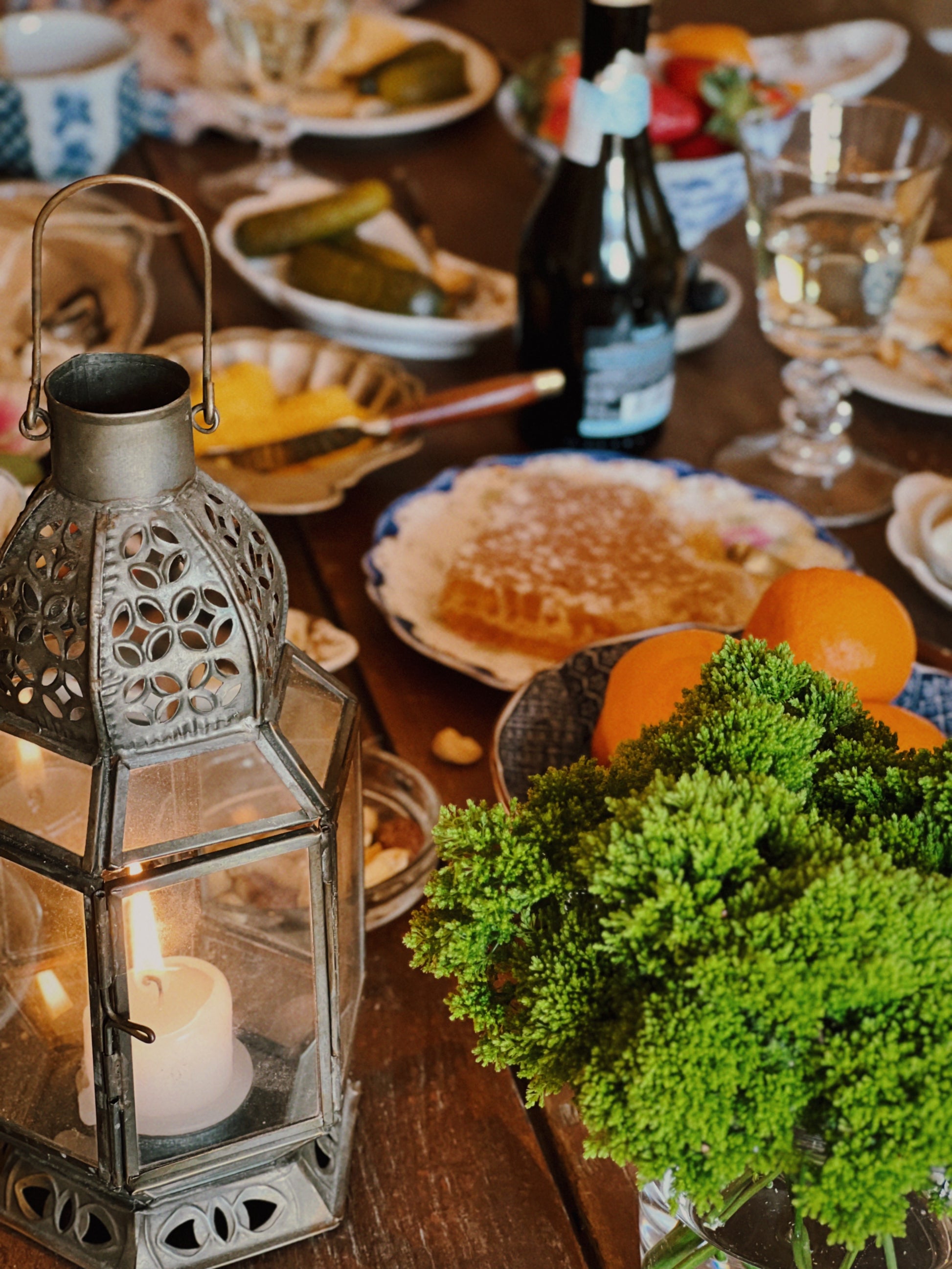 angled view of a tabletop set with charcuterie and a moroccan style candle lantern as table decor
