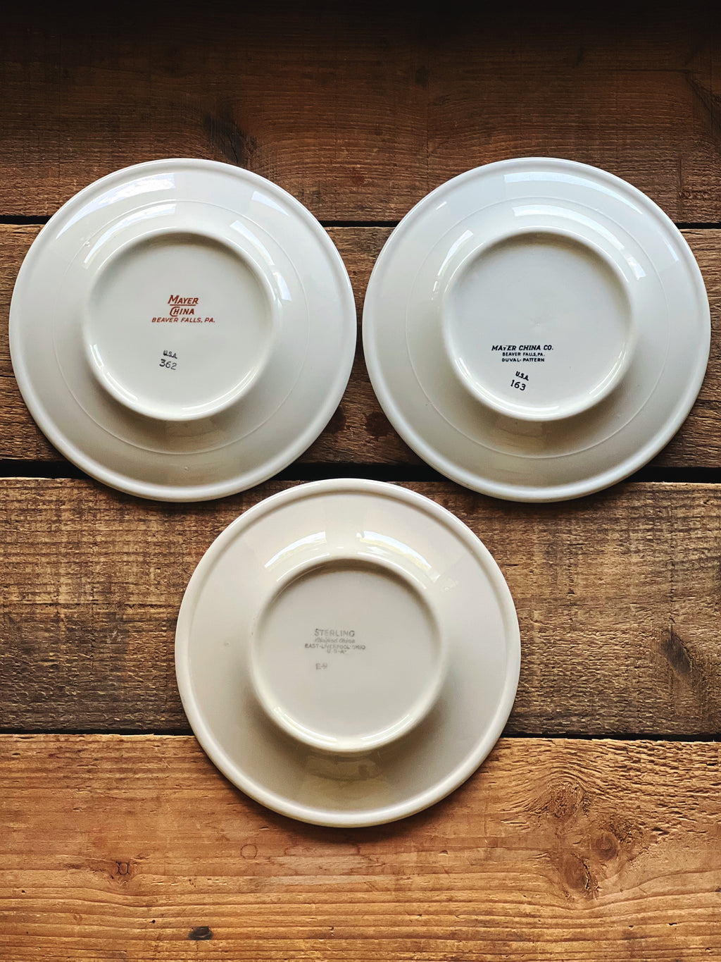 bottom view of three small vintage plates showing maker marks and condition