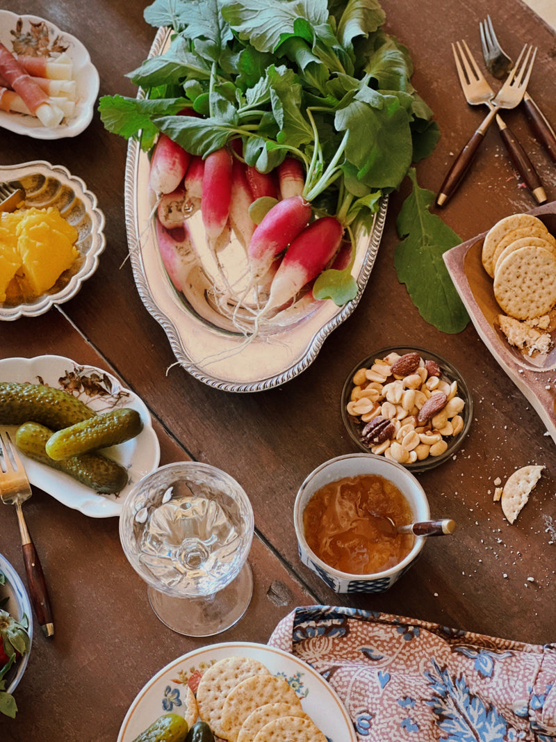 carved wood snack dish with olives, nuts and honey on rustic table setting