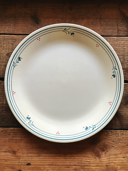 Vintage Corelle Country Violets dinner plate on rustic wood surface with blue floral rim