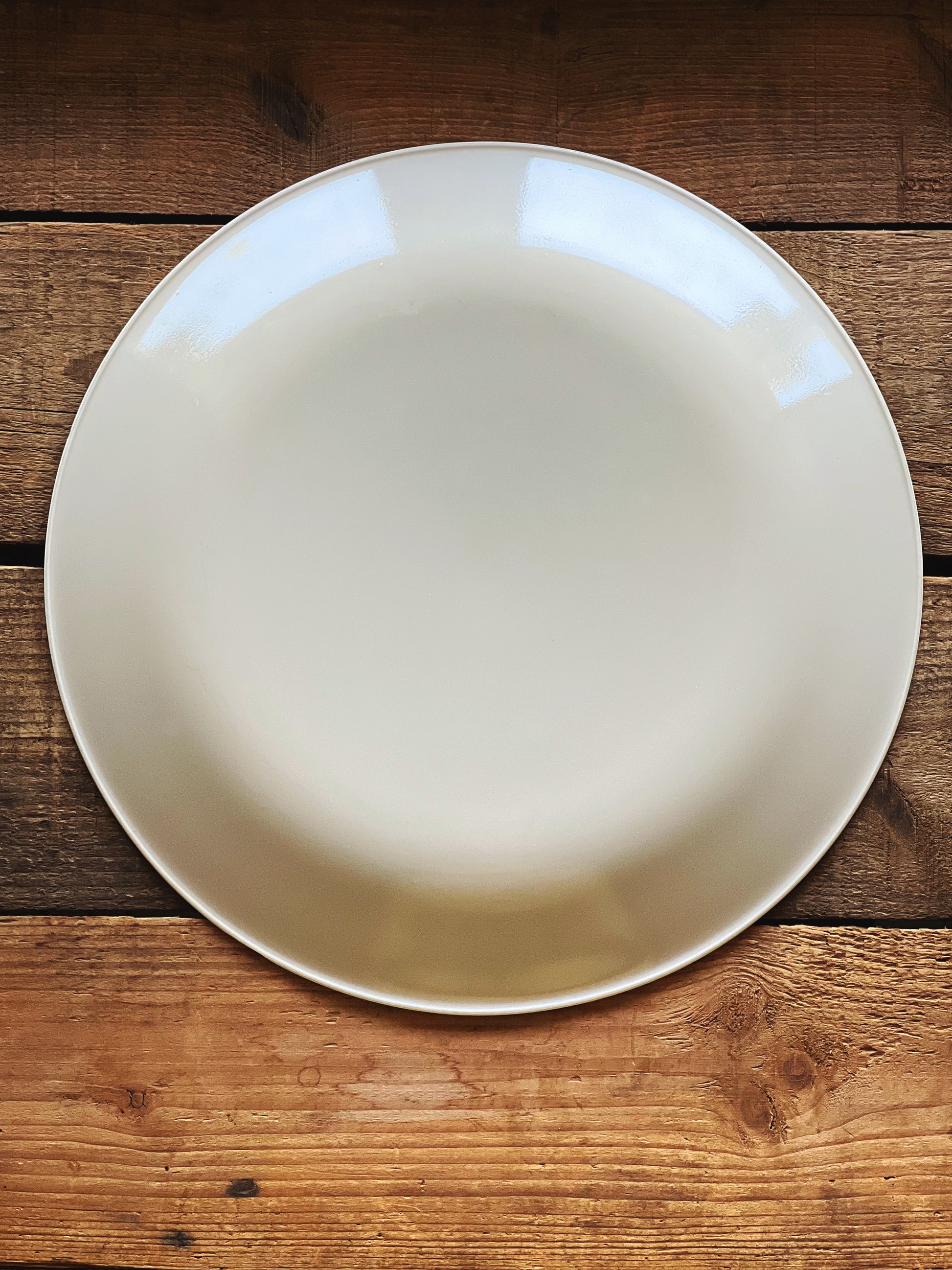 Single vintage Corelle dinner plate centered on wood table, minimal styling 