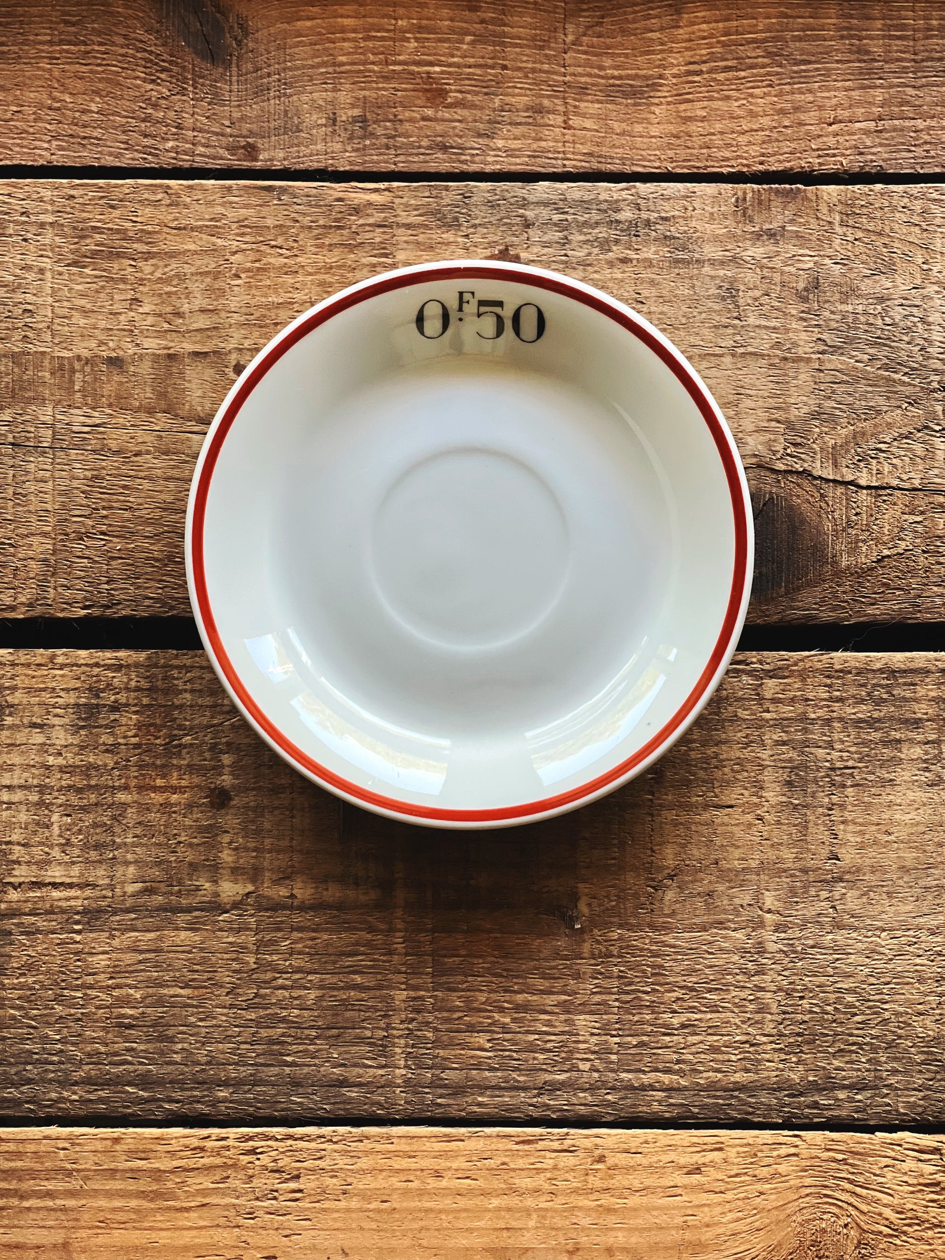 Pillivuyt France white porcelain saucer with red rim detail on rustic wood surface