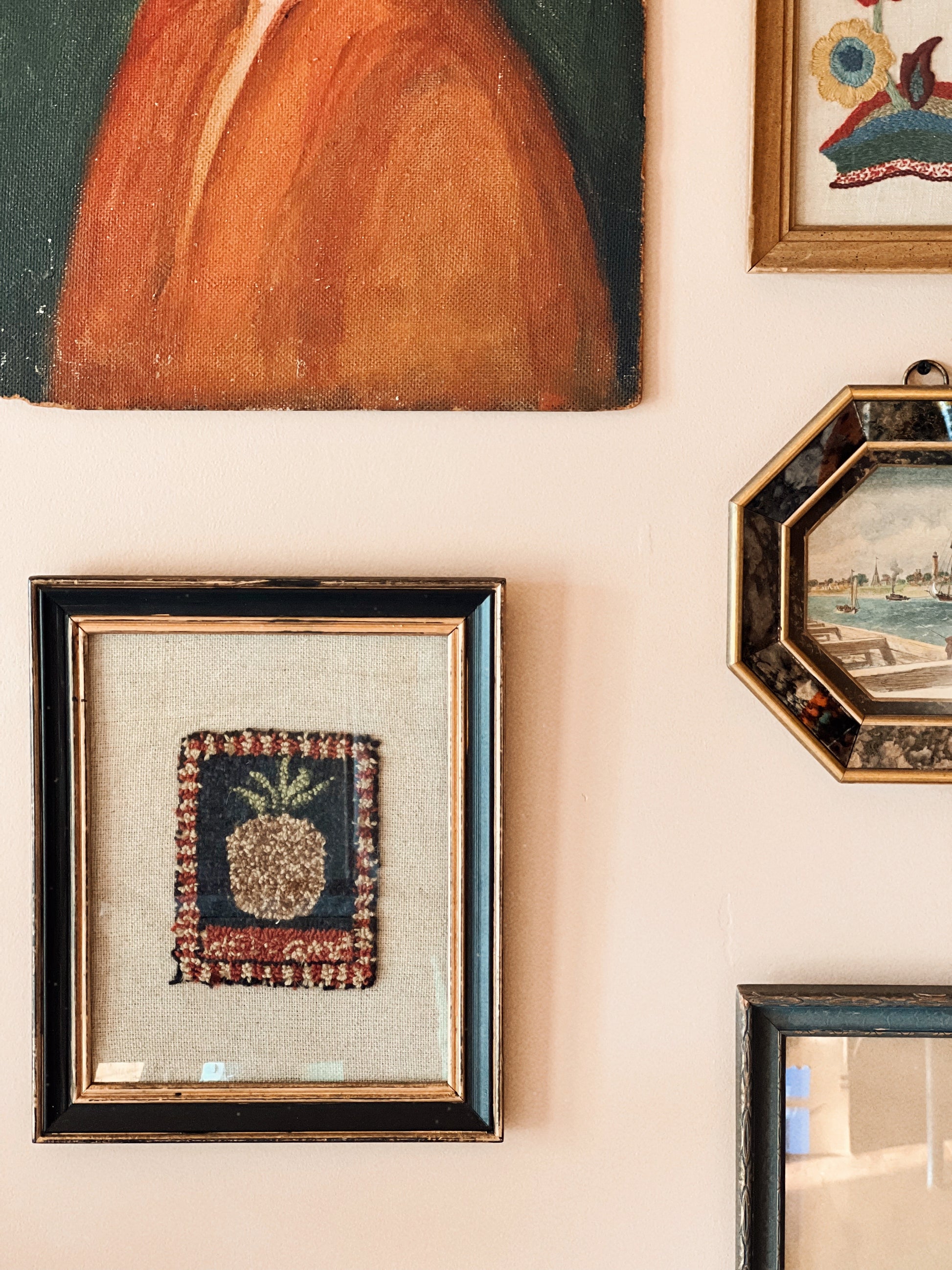 Closer view of vintage punch needle pineapple embroidery in black and gold frame on neutral linen backing