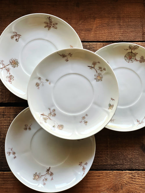 Set of four vintage Charles Field Haviland Limoges floral saucers photographed on a warm wood tabl