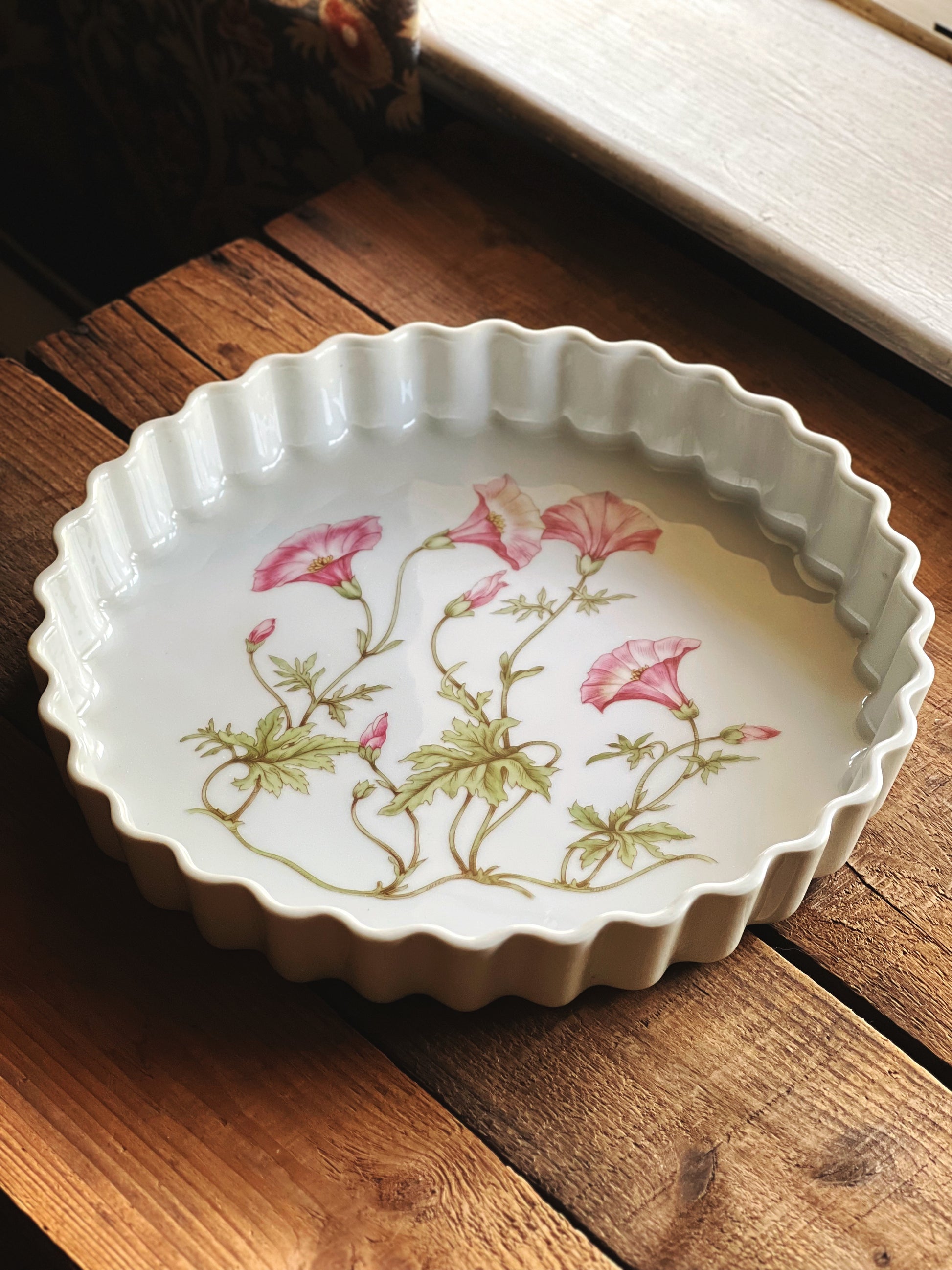 Pillivuyt France tart pan with fluted edges and pink morning glory floral design styled on rustic wood table