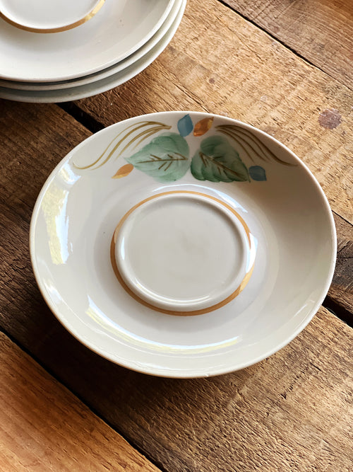 Set of 4 vintage hand painted floral saucers with green and blue detail styled on rustic wood table