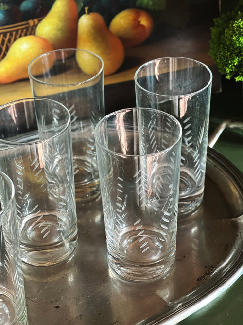 Overhead view of a set of vintage etched highball glasses displayed on a silver tray 