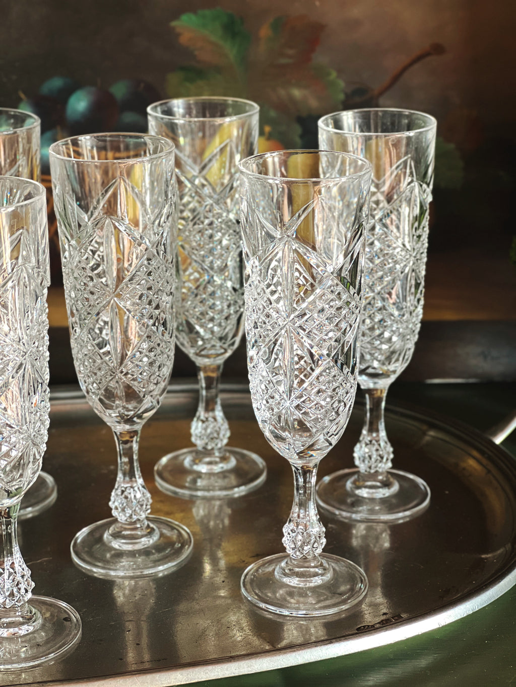 Front view of a set of crystal glasses on a reflective surface with a blurred background