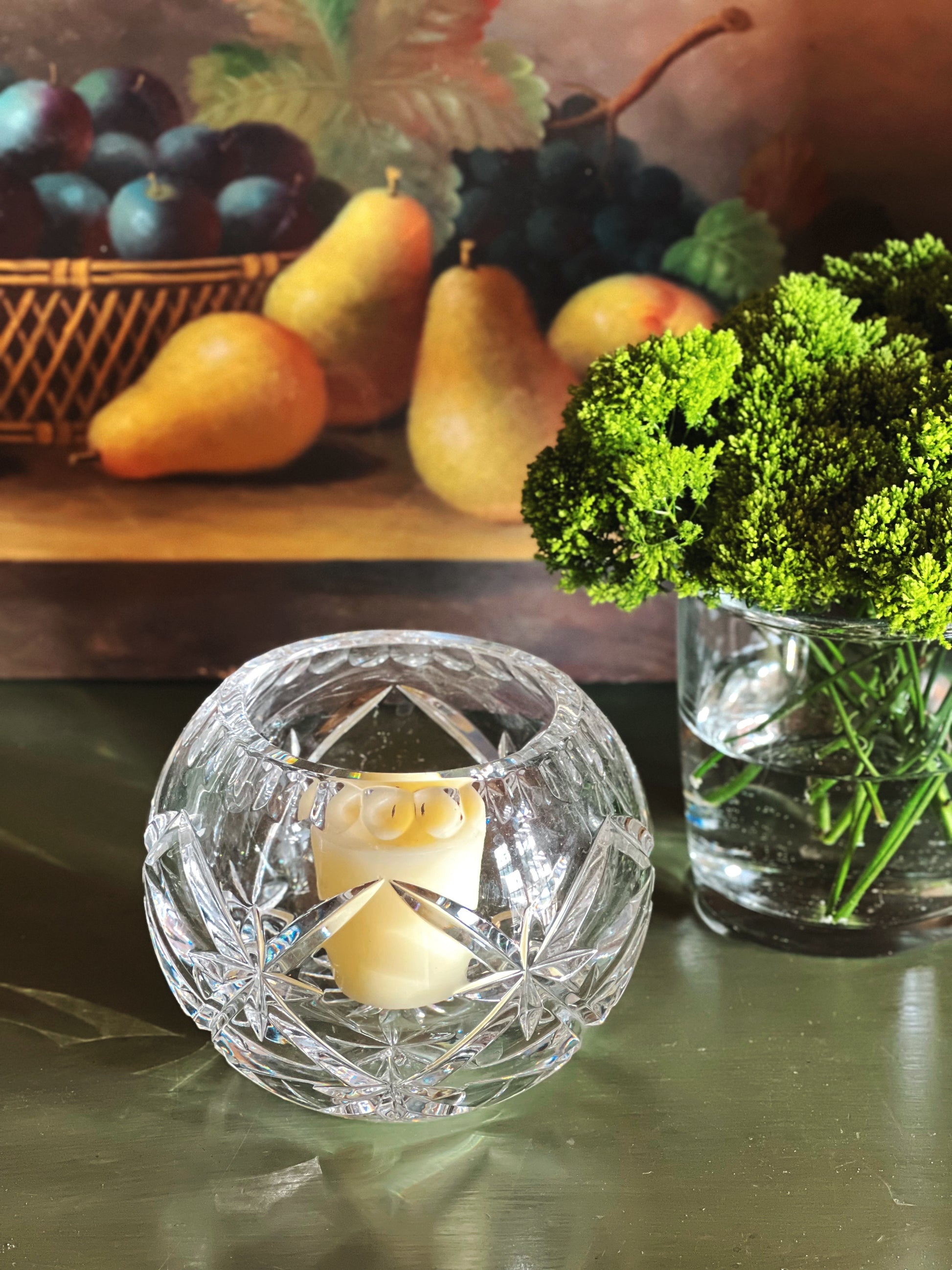 Round vintage crystal votive holder with starburst cut detail on dark green surface