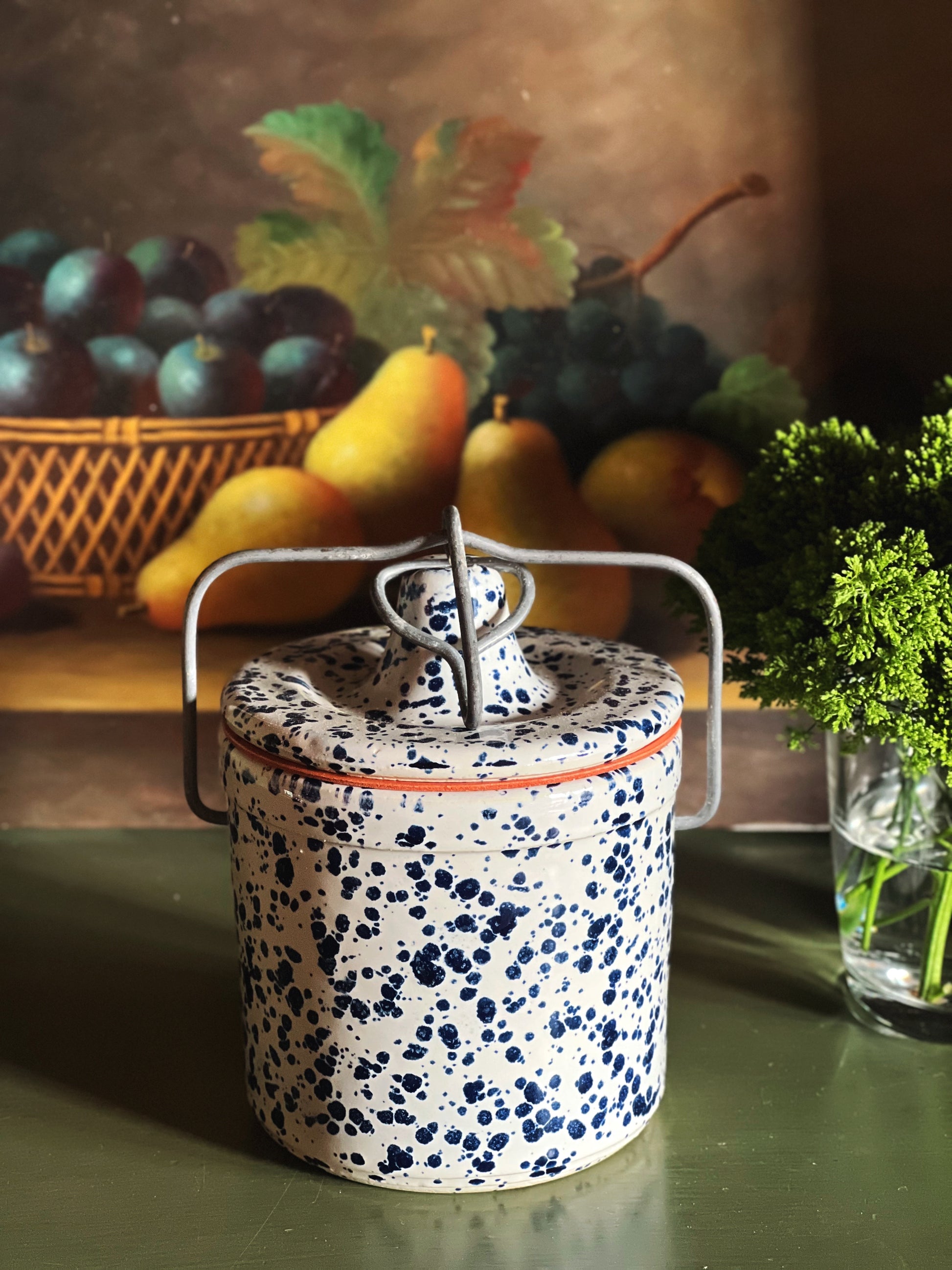 Vintage spongeware stoneware crock with lid and bail handle styled with fresh produce on green surface
