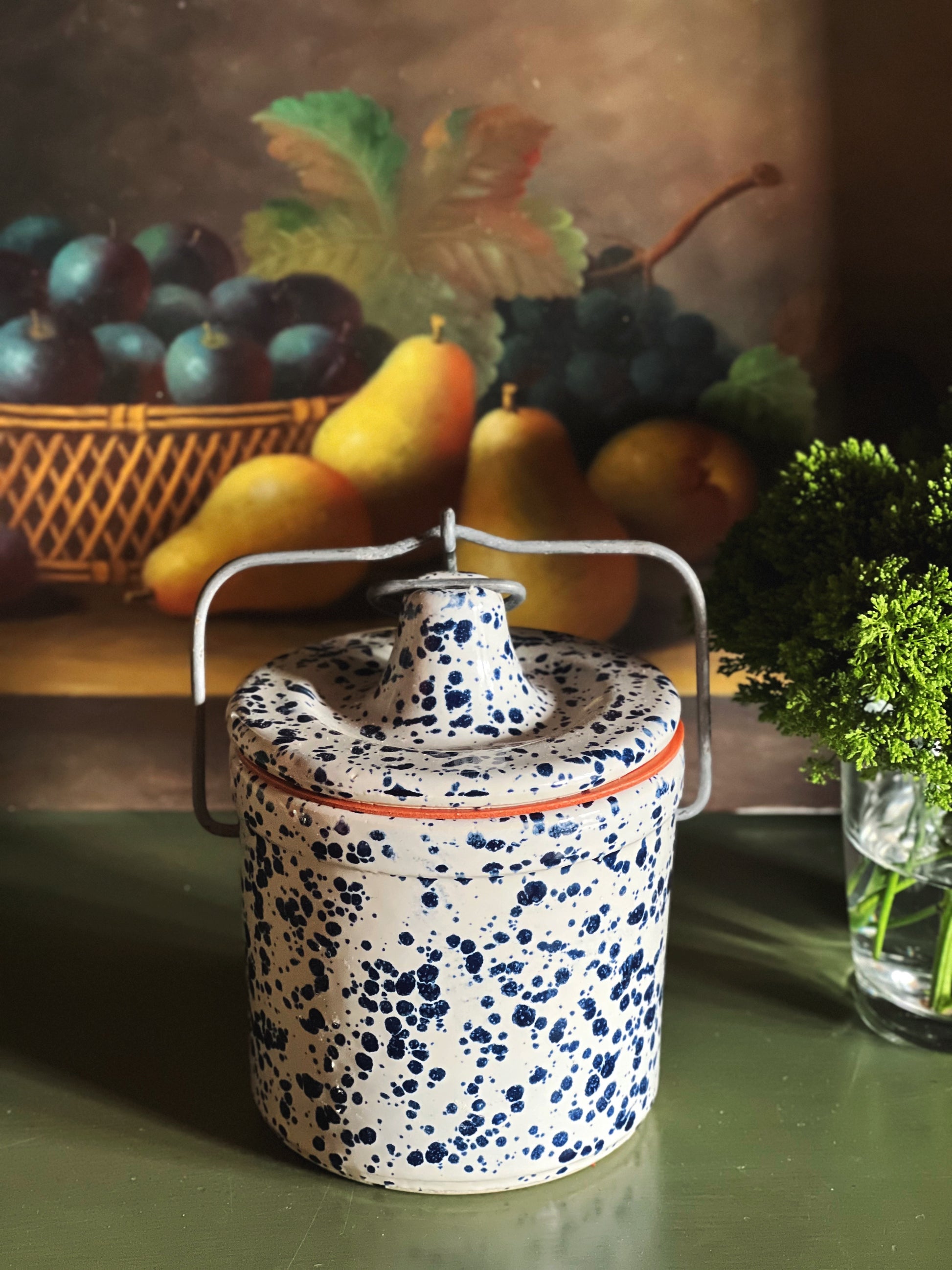 Side view of vintage spongeware crock with metal bail handle and lid attached