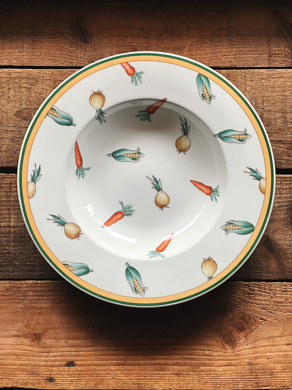 Overhead view of a rimmed soup bowl with a vegetable motif