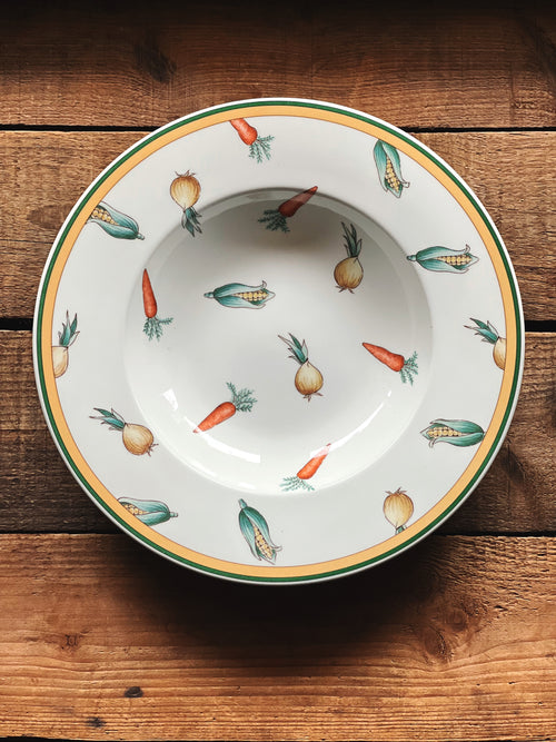 Overhead view of a rimmed soup bowl with a vegetable motif