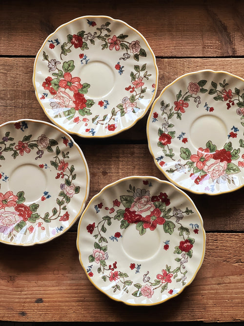 Stacked vintage floral saucers with buttery yellow background and scattered wildflower motif