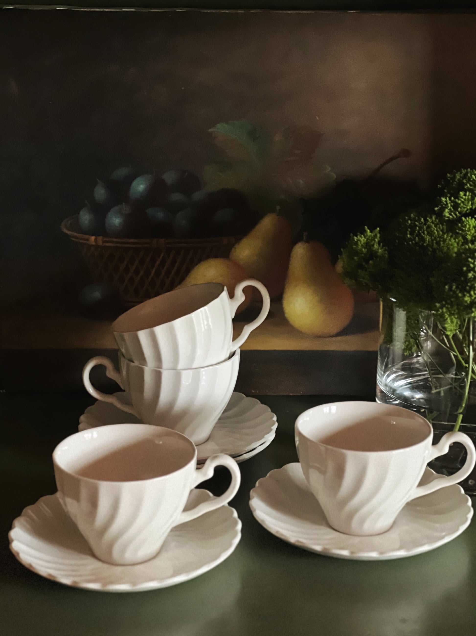 Vintage Johnson Brothers Regency white ironstone teacups and saucers styled on a dark green surface with pears and citrus