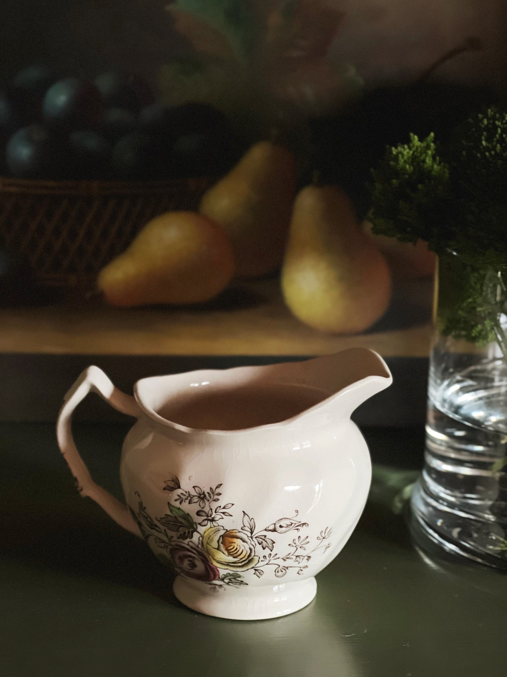 Side view of a vintage Johnson brothers Sheraton creamer with a moody still life background
